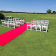 A stunning wedding ceremony set up on a golf course, complete with a luxurious 6m red carpet hire.