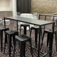 A room with a black rectangular table and stools in it.