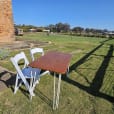 Two white chairs and a signing table in a grassy field.