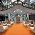 An orange carpet and white furniture, including a white round coffee table, in a mall.