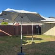 A backyard with a white market umbrella and chairs.