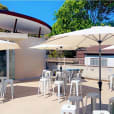 A patio with white market umbrellas and stools available for hire.