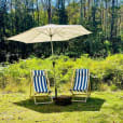 Two chairs shaded by a market umbrella in a grassy area.