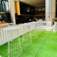 A white table and chairs set on a lush green grass lawn, creating a serene outdoor oasis within a building.