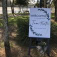 A welcome to the bride sign displayed on a black wooden easel in front of a tree.