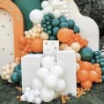         An orange and white balloon arch with green and large white balloons.