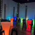 A Glow Cocktail Bar, adorned with colorful lights and accompanied by stools for hire.