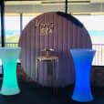 A glow cocktail bar table hire set up in front of a window, featuring a photo booth.