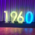 The number 70 is glowing on a stage in front of a curtain.