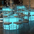 A Round Glow Banquet Table with blue lights in the middle of a room.