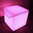 A pink LED cube table illuminates a dark room.
