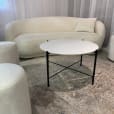 Black cross coffee with white top table next to a Ottoman stool