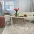 A white lounge setting with a pink velvet ottoman stool