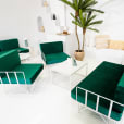 A white wire armchair lounge with green velvet cushions