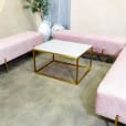 Three pink velvet ottoman benches with a coffee table in the middle