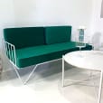 Wire sofa lounge with green velvet cushions behind a coffee table