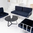 A white wire lounge set with black velvet cushions around a coffee table