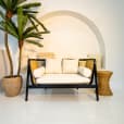 A black rattan sofa lounge set up next to a palm tree