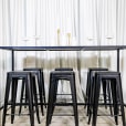 A black rectangular tapas table with stools underneath it