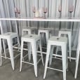 A white rectangular tapas table with stools underneath it