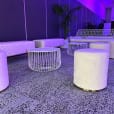 A white wire table next to a lounge setting in beautiful purple light