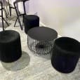 Black wire round coffee table next to black ottoman stools