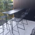 Black hairpin high bar table set up on a balcony with wire stools