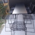 Hairpin high bar table with black top set up with wire chairs on a balcony