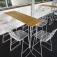 Timber top hairpin table surrounded by white wire stools