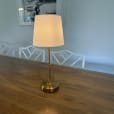 A white shade table lamp on a timber table