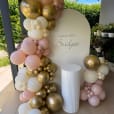 White ribbed plinth placed in front of a custom birthday backdrop, decorated with gold, blush pink, and ivory balloon garland for an 18th birthday celebration.