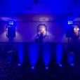 Blue battery-operated par can uplights illuminating a DJ booth and speakers in a dark event space, creating a vibrant atmospheric wash across the room.