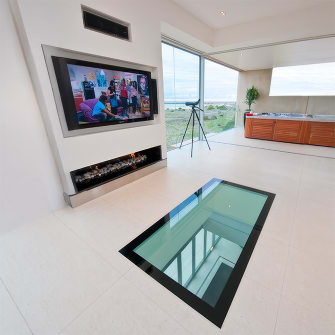 A glass floor in the living room of a modern beachfront home