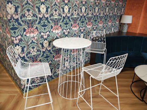 White wire table and stools in front of patterned wallpaper