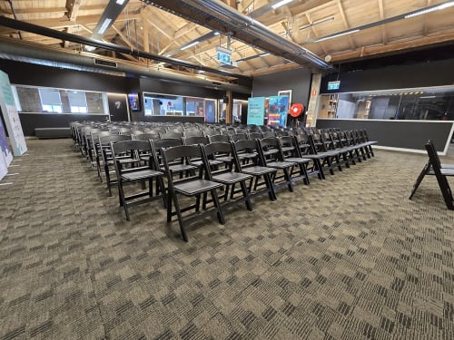 Lots of black plastic chairs set up for a conference