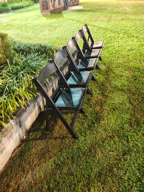 Black plastic folding chairs in a park