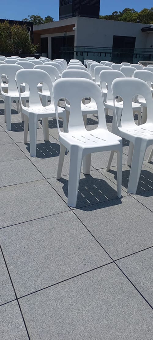 Lots of white stackable chairs set up at an outdoor conference