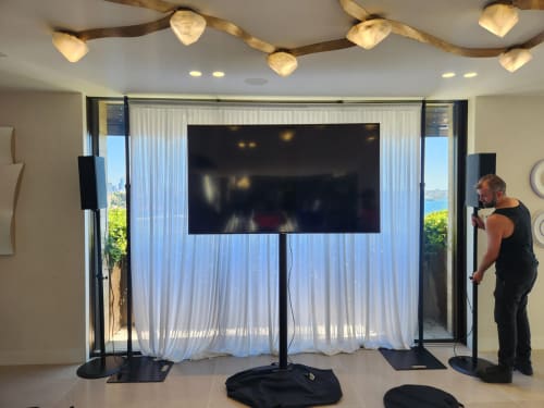 A TV stand with PA speakers being set up, ready for a party