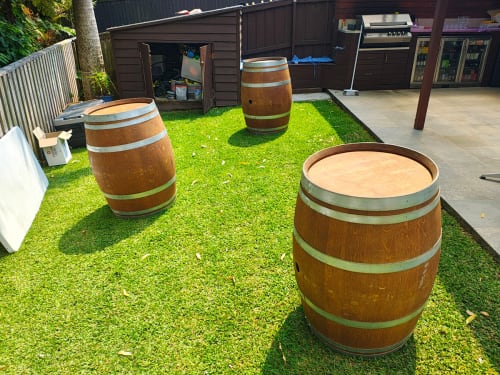 Three wine barrels spread out across the lawn near a barbecue area