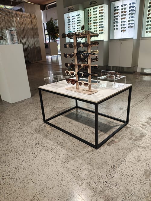 Our black-framed coffee table with a white top and a sunglasses display on top of it