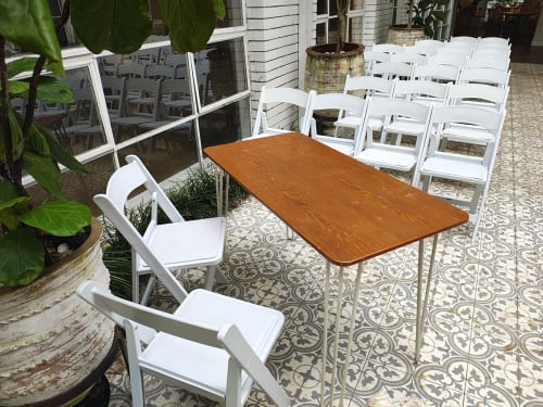 A bunch of white plastic folding chairs and a timber table