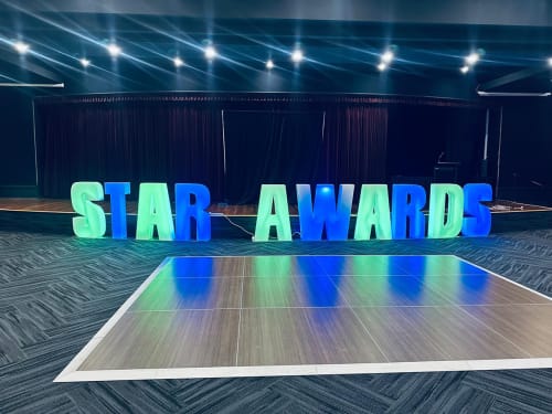 Glow letters that spell 'STAR AWARDS' in front of an Advance for backdrop