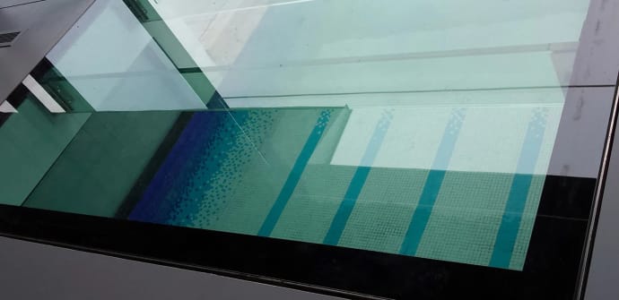 A residential glass floor looking down into a pool