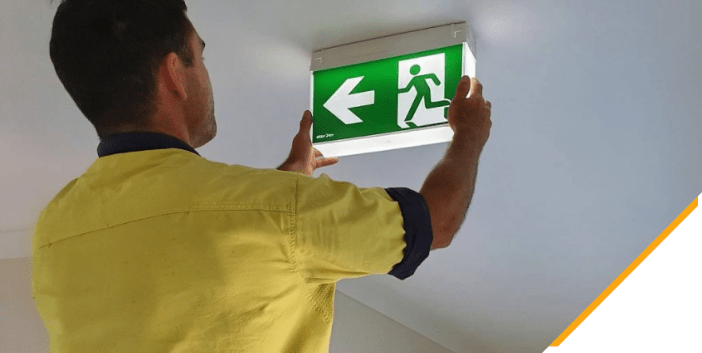An electrician installing emergency lighting in a commercial building