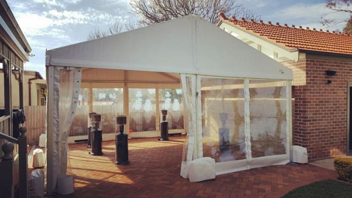 A white tent is set up in front of a house.
