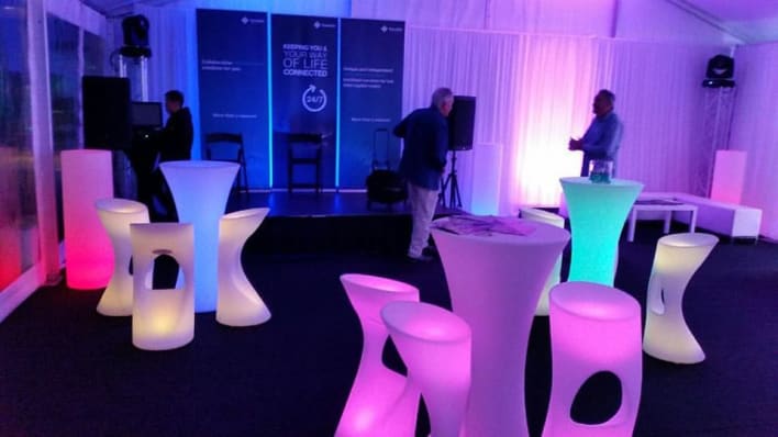 A group of colorful stools and tables in a tent.