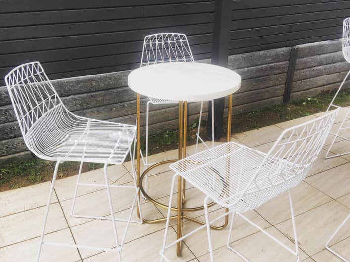 A set of white stools and a table on a patio.
