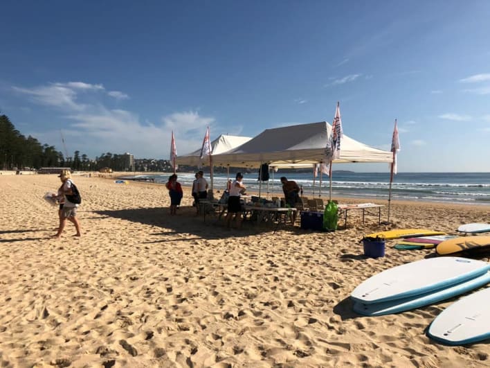 A group of people standing on the beach with surfboards.