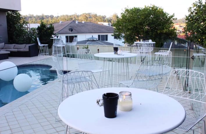 A white table and chairs next to a swimming pool.