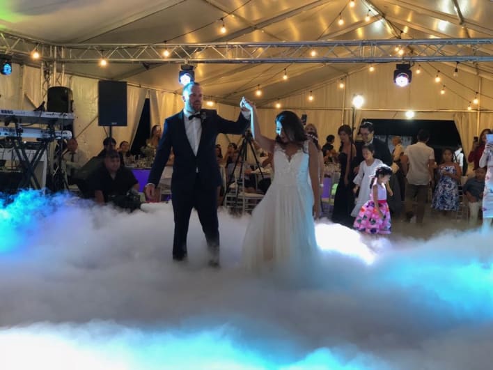 A bride and groom standing on a cloud of smoke.